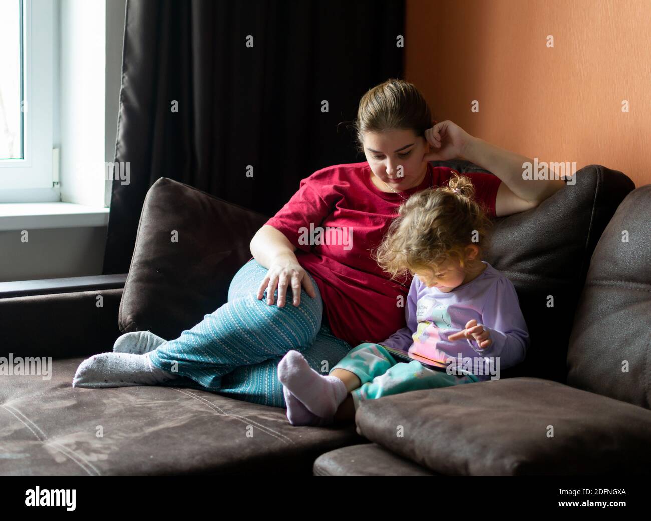 Madre e figlia a casa utilizzano un tablet pc. Maternità, passare il tempo con un bambino. Amore parentale. Foto Stock