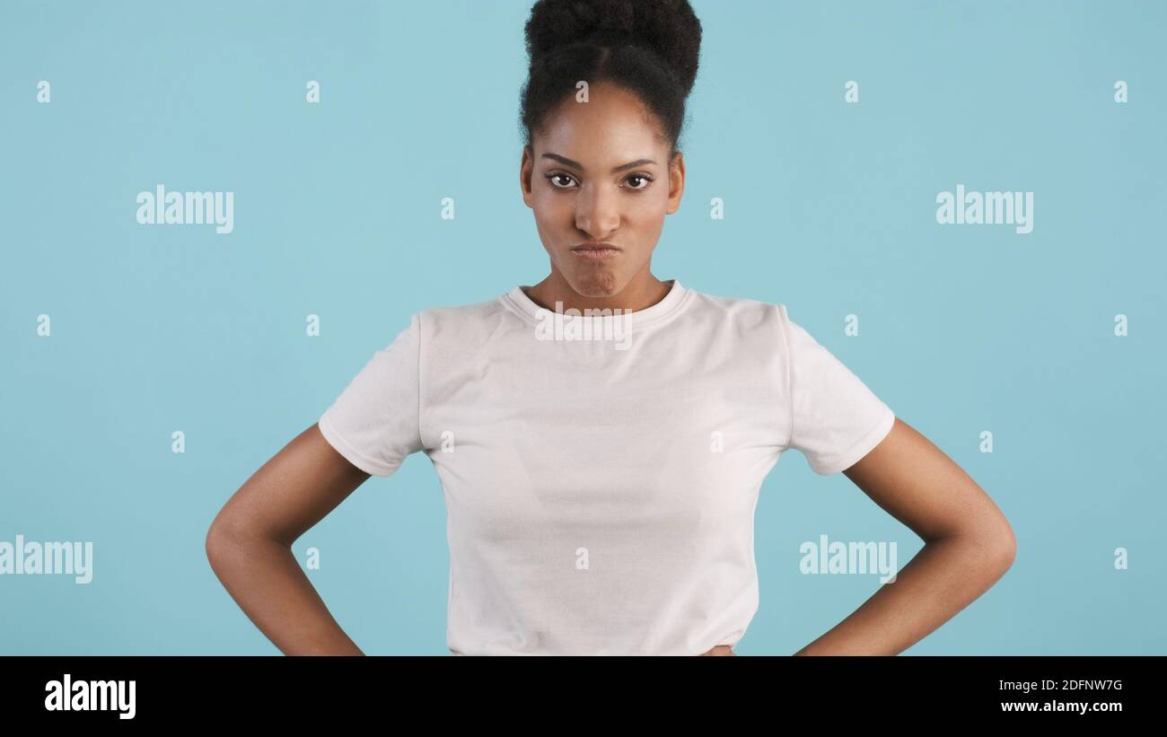 Ritratto di arrabbiato seria ragazza afroamericana che guarda aggressivamente dentro fotocamera su sfondo colorato Foto Stock