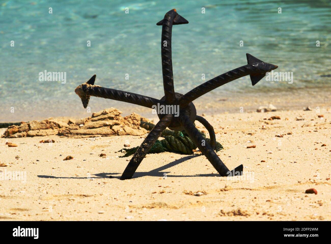 Un'ancora a cinque punte che riposa nella sabbia su una spiaggia in Stone Town, Zanzibar. Foto Stock