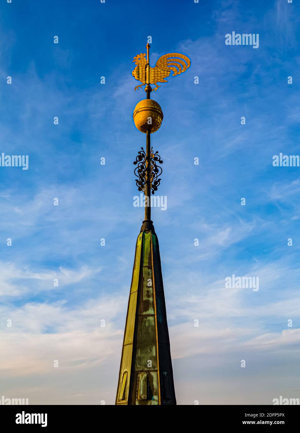 Grande paletta meteorologica dorata montata sulla sommità di un'enorme torre della chiesa. Primo piano dell'antenna. Foto Stock