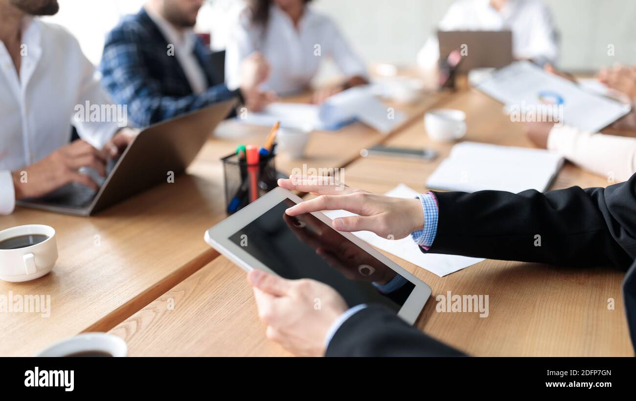 Tablet nelle mani di un uomo d'affari durante la riunione d'affari in ufficio, Closeup Foto Stock
