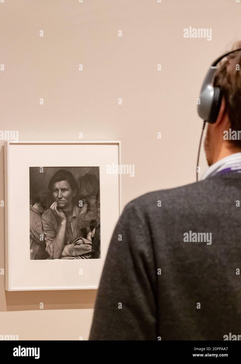 Un giovane con le cuffie guarda la fotografia del Migrant di Dorothea Lange Madre in Moma museo a New York City Foto Stock