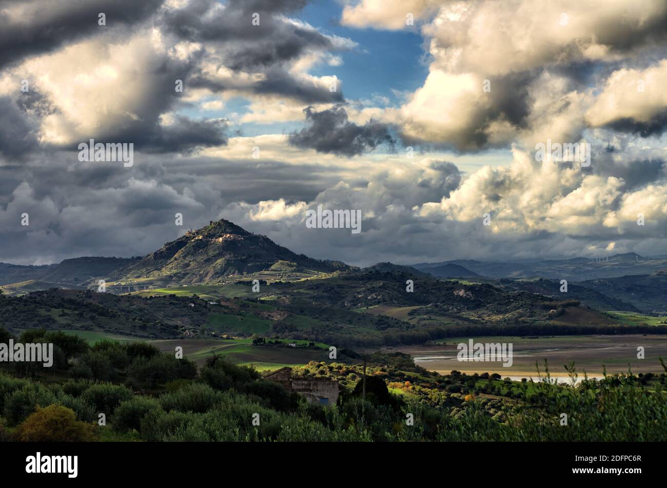 Suggestivo paesaggio della campagna siciliana, il monte della città di Agira spicca tra il tempo tempestoso su terreni collinari dell'entroterra siciliano Foto Stock