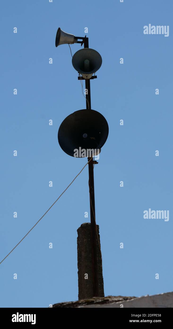 Un'immagine verticale di un palo con altoparlanti su un sfondo blu cielo Foto Stock