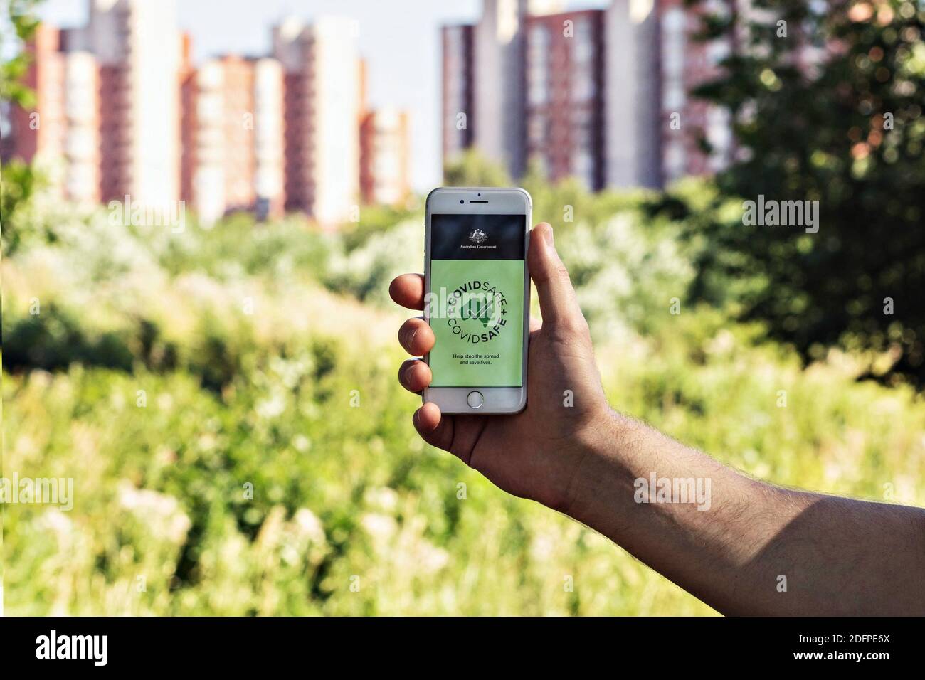 La mano di un uomo tiene un telefono con l'app CovidSafe Foto Stock