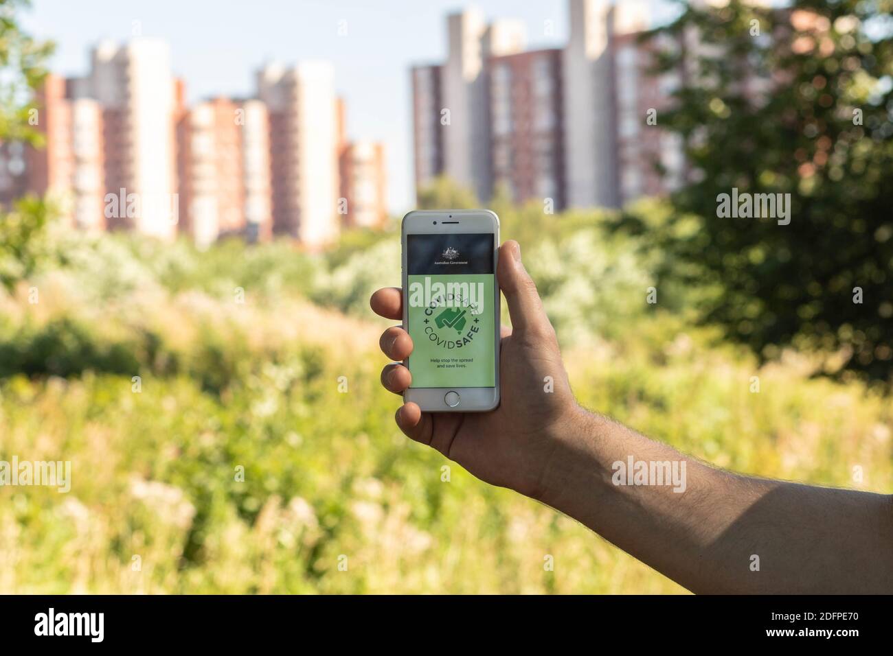 La mano di un uomo tiene un telefono con l'app CovidSafe. Foto Stock