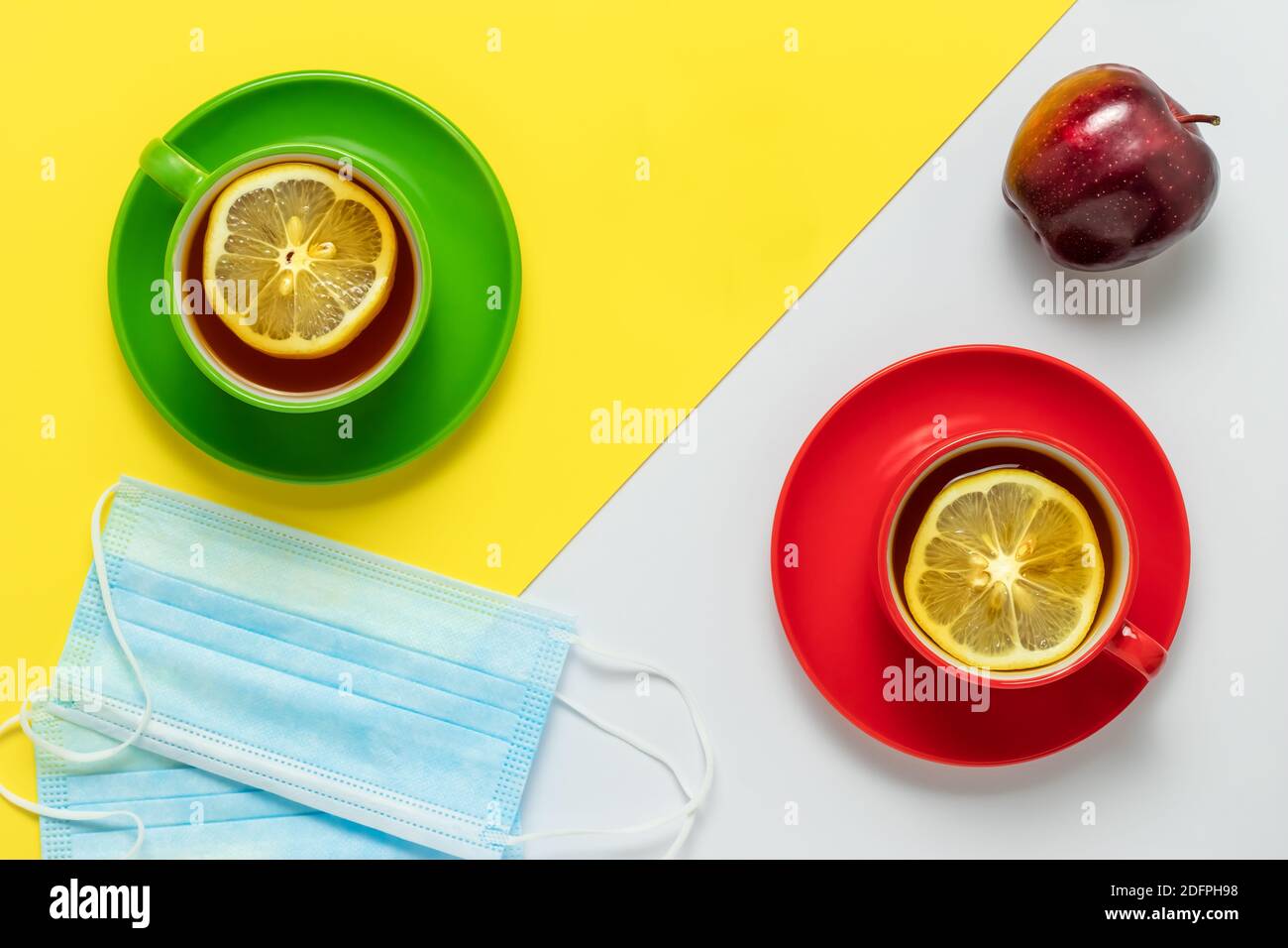 Tè con fette di limone al mattino. Festa del tè per due e frutta di mela. Due mascherine protettive sul tavolo nel caffè. Due tazze con rosso e gre Foto Stock