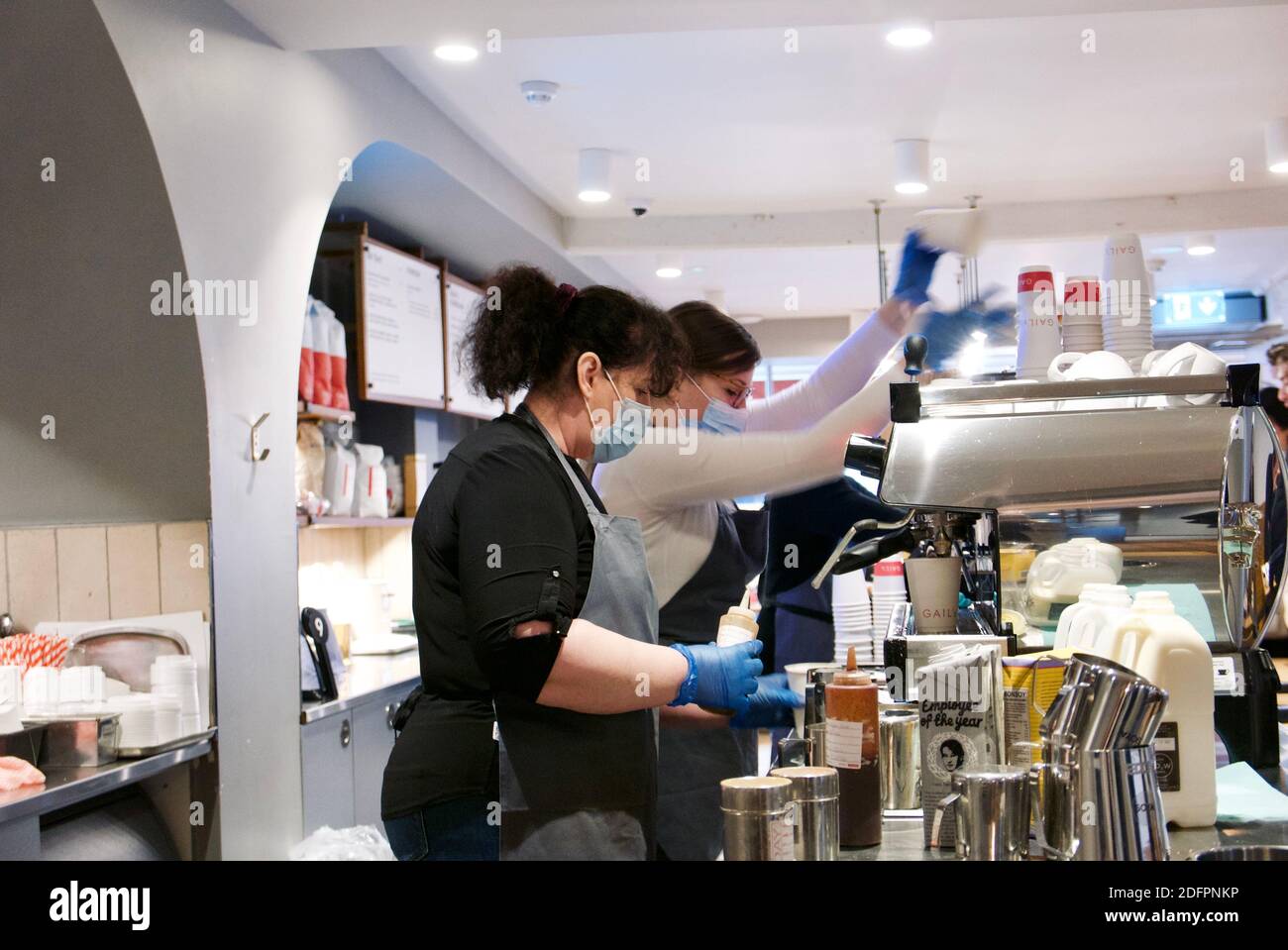 Due baristi che servono caffè da una macchina espresso nella panetteria e caffetteria Gails. Foto Stock