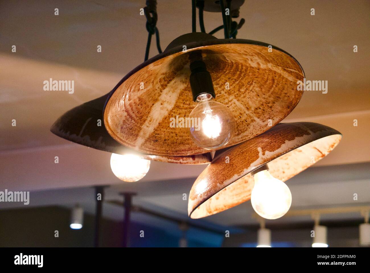 Lampada da soffitto in un ristorante con lampada a vista e paralume decorativo. Foto Stock