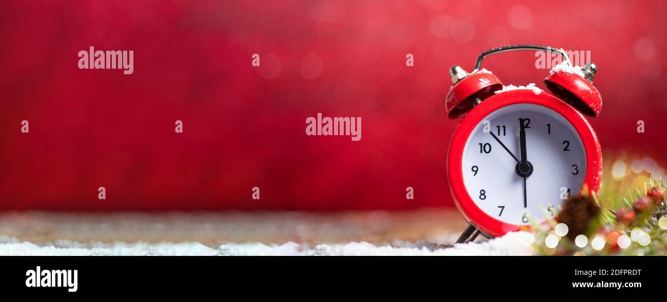 Orologio vintage che si avvicina alla mezzanotte contro sfondo rosso di Natale con ampio spazio per la copia. Banner per le festività di Capodanno con ampio spazio per il testo Foto Stock