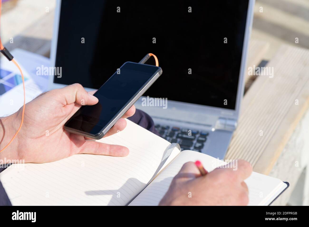 Uso cellulare e laptrop all'aperto. Uomo che utilizza dispositivi di comunicazione digitale seduto su una panca presso il parco della città cellulare wi-fi dati serv Foto Stock