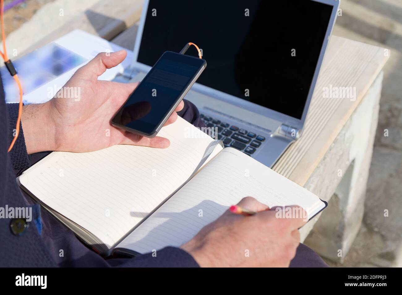 Uso cellulare e laptrop all'aperto. Uomo che utilizza dispositivi di comunicazione digitale seduto su una panca presso il parco della città cellulare wi-fi dati serv Foto Stock