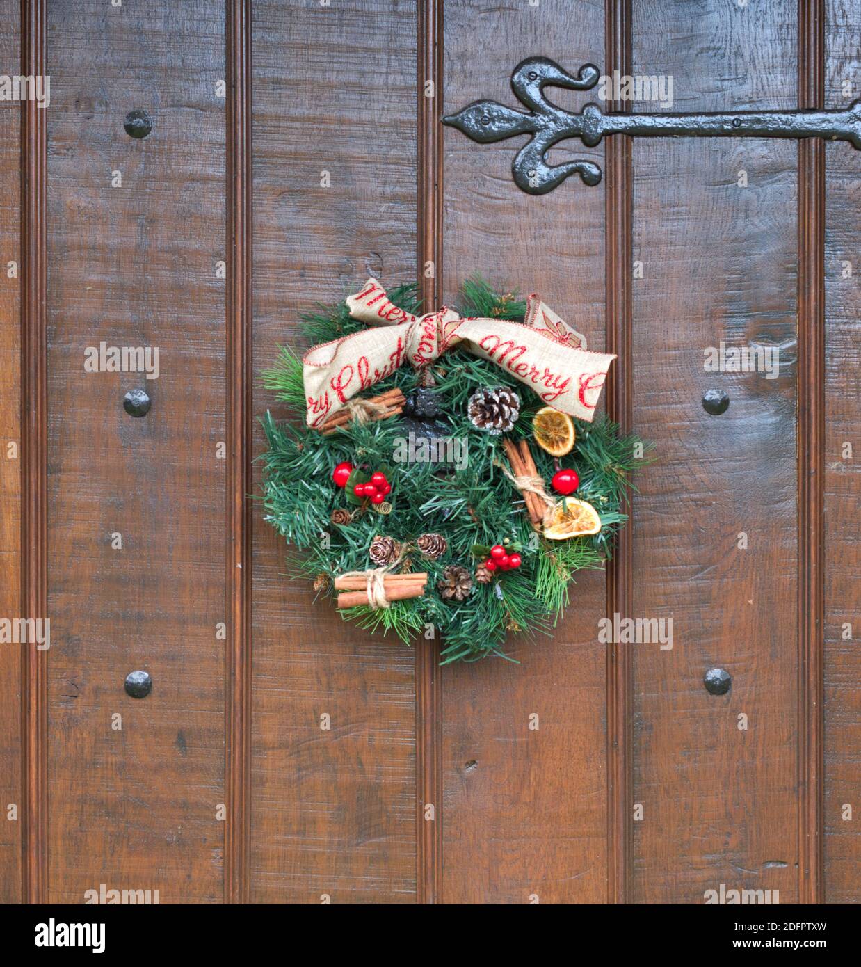 Una corona di Natale fatta in casa su una porta di legno con finiture nere. Foto Stock