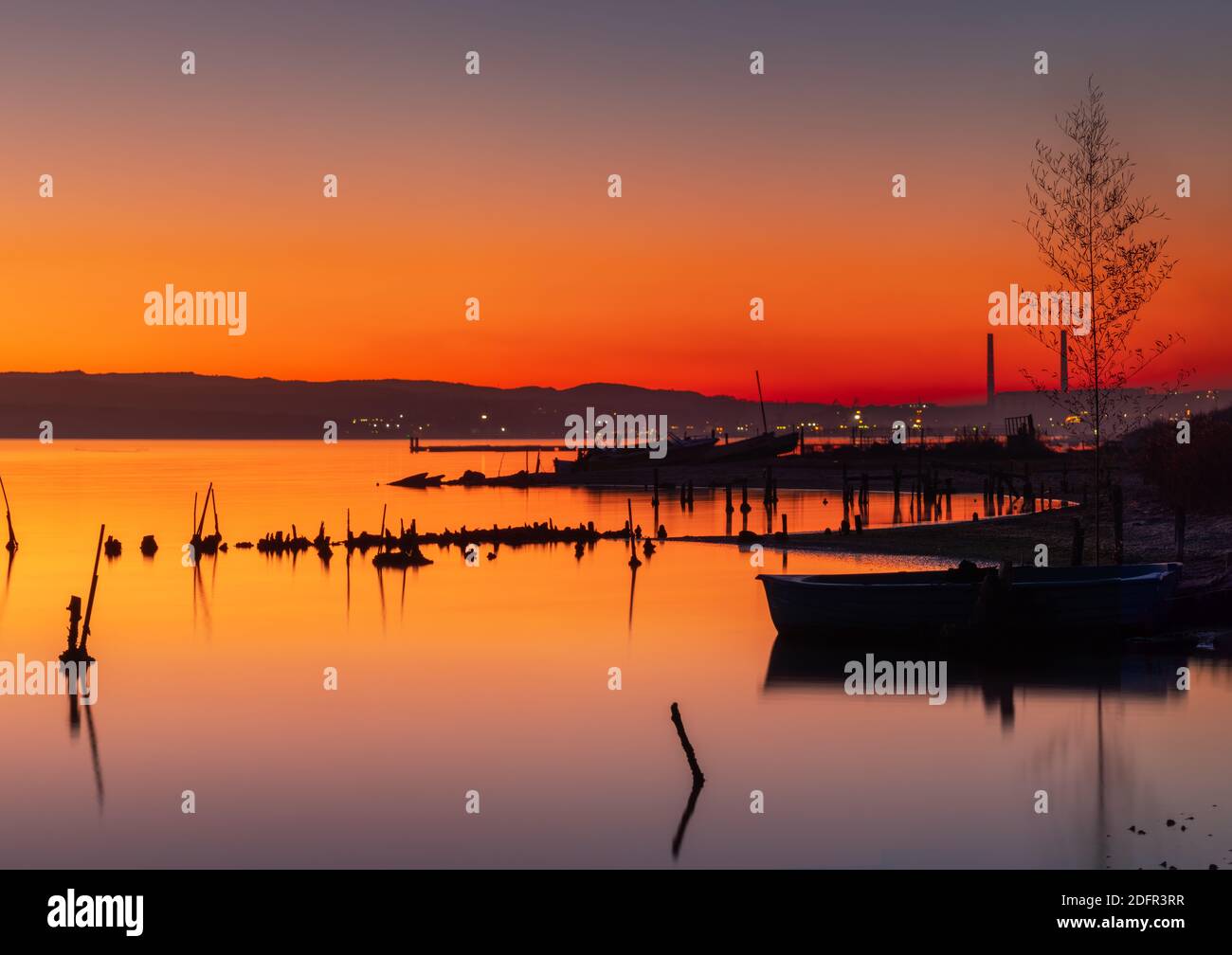 Tramonto sul lago, molo in legno e vecchia barca da pesca Foto Stock