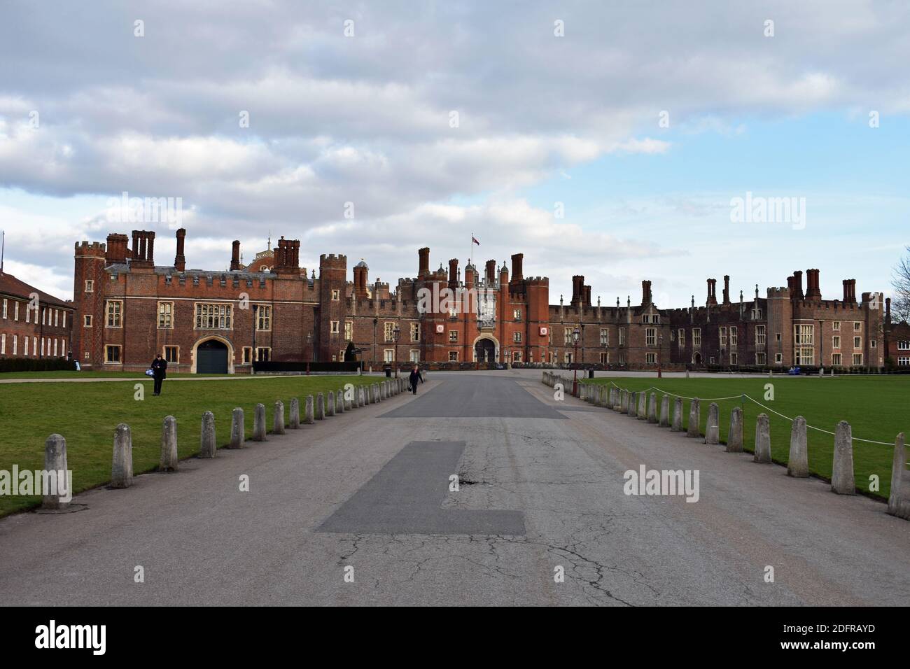 L'entrata principale all'Hampton Court Palace, Londra. Un grande vialetto conduce all'entrata e alla facciata in mattoni Tudor. I visitatori camminano intorno ai giardini. Foto Stock