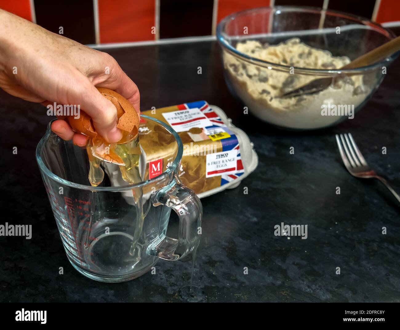 Norwich, Norfolk, Regno Unito – Dicembre 06 2020. Fotografia editoriale illustrativa di un panettiere domestico non identificabile che cricchiera un uovo di gamma libera di marca Tesco Foto Stock