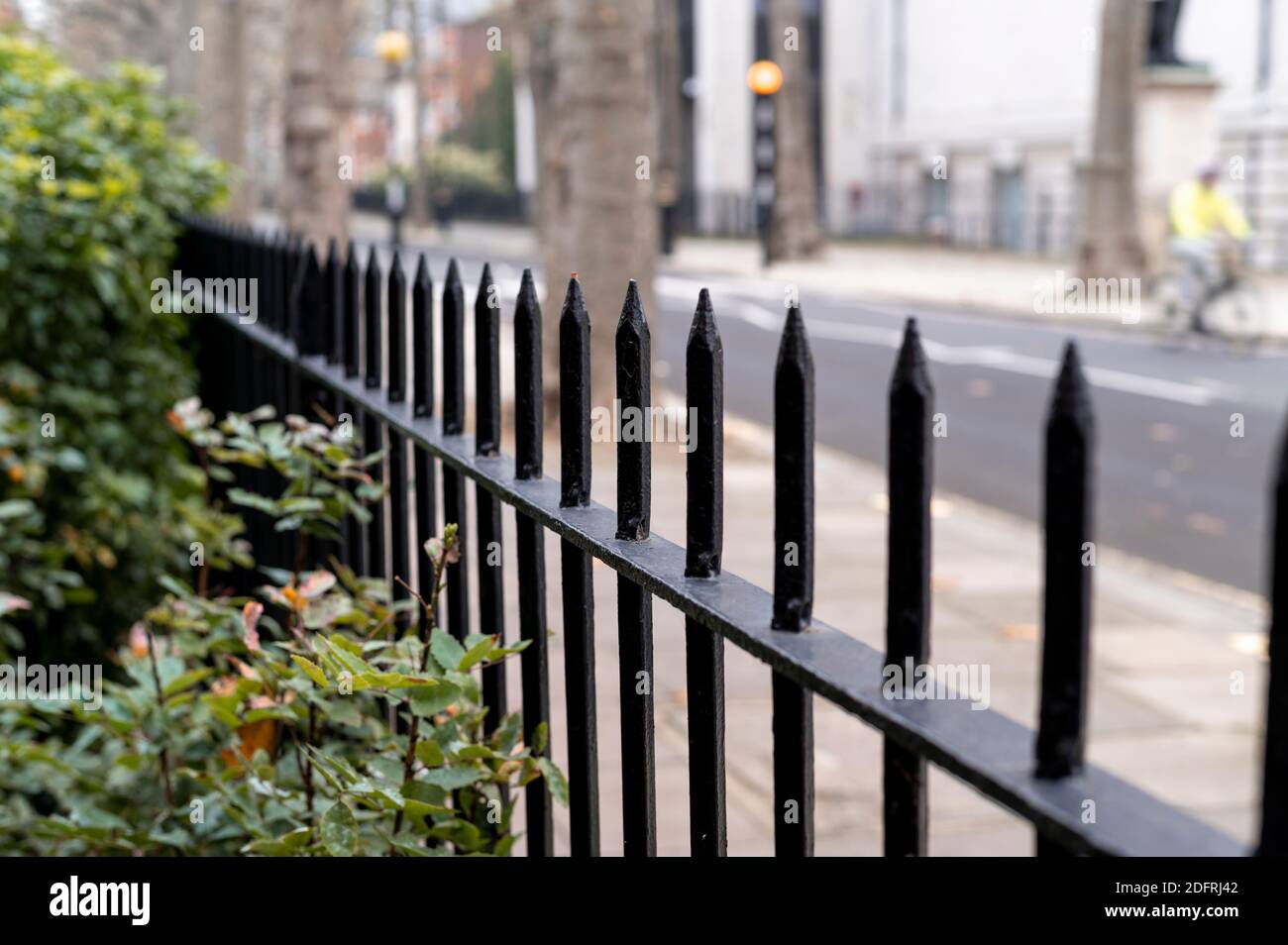 Primo piano di una ringhiera nera in un parco con Sfondo sfocato di una via di Londra Foto Stock