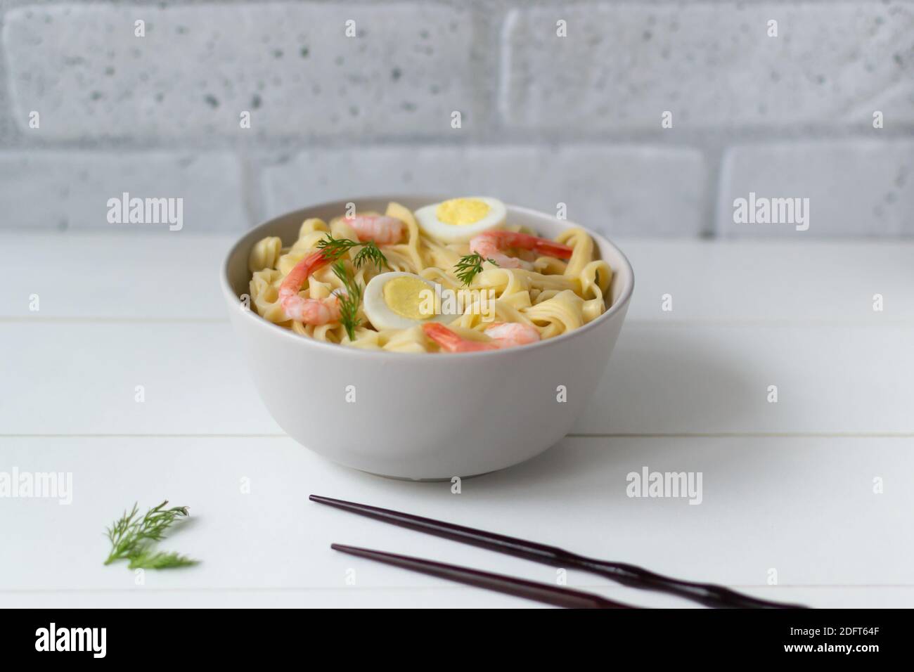 Noodle naturali fatte in casa con gamberi e uova di quaglia su uno sfondo chiaro. Orientamento orizzontale. Spazio di copia. Messa a fuoco selettiva. Foto Stock