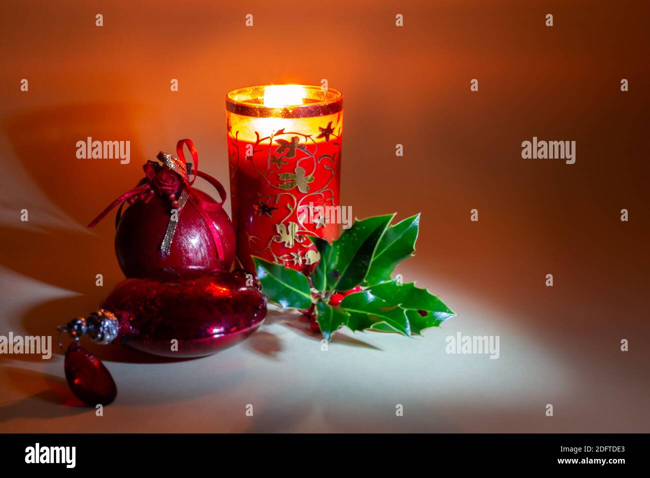 Rosso Natale baubles e un ramo di agrifoglio da luce. Spirito di festa. Foto Stock