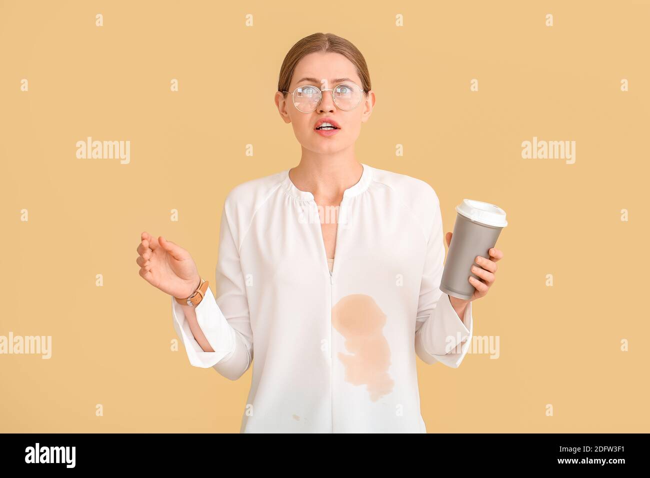 Giovane donna stressata con macchie di caffè sulla camicia sfondo a colori Foto Stock