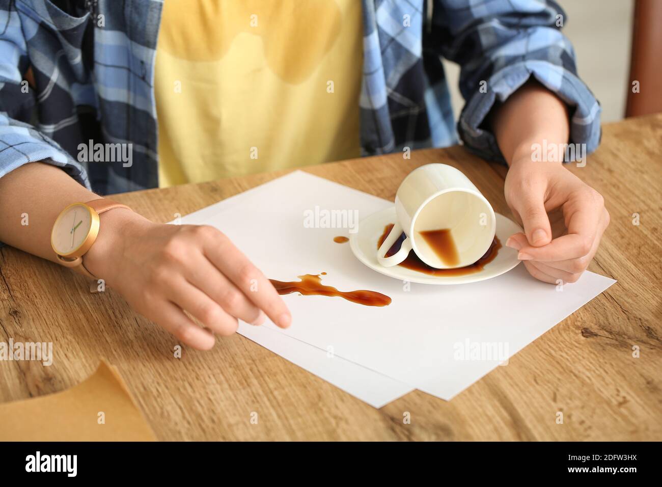 Donna con macchie di caffè sulla sua t-shirt e caffè versato in cucina Foto Stock