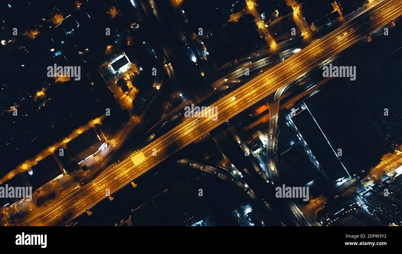 In cima al semaforo notturno dell'autostrada a bordo di strade illuminate. Paesaggio urbano filippino su strada illuminata da lanterne. Architettura moderna del centro: Grattacieli edifici. Città al crepuscolo cinematografica Foto Stock