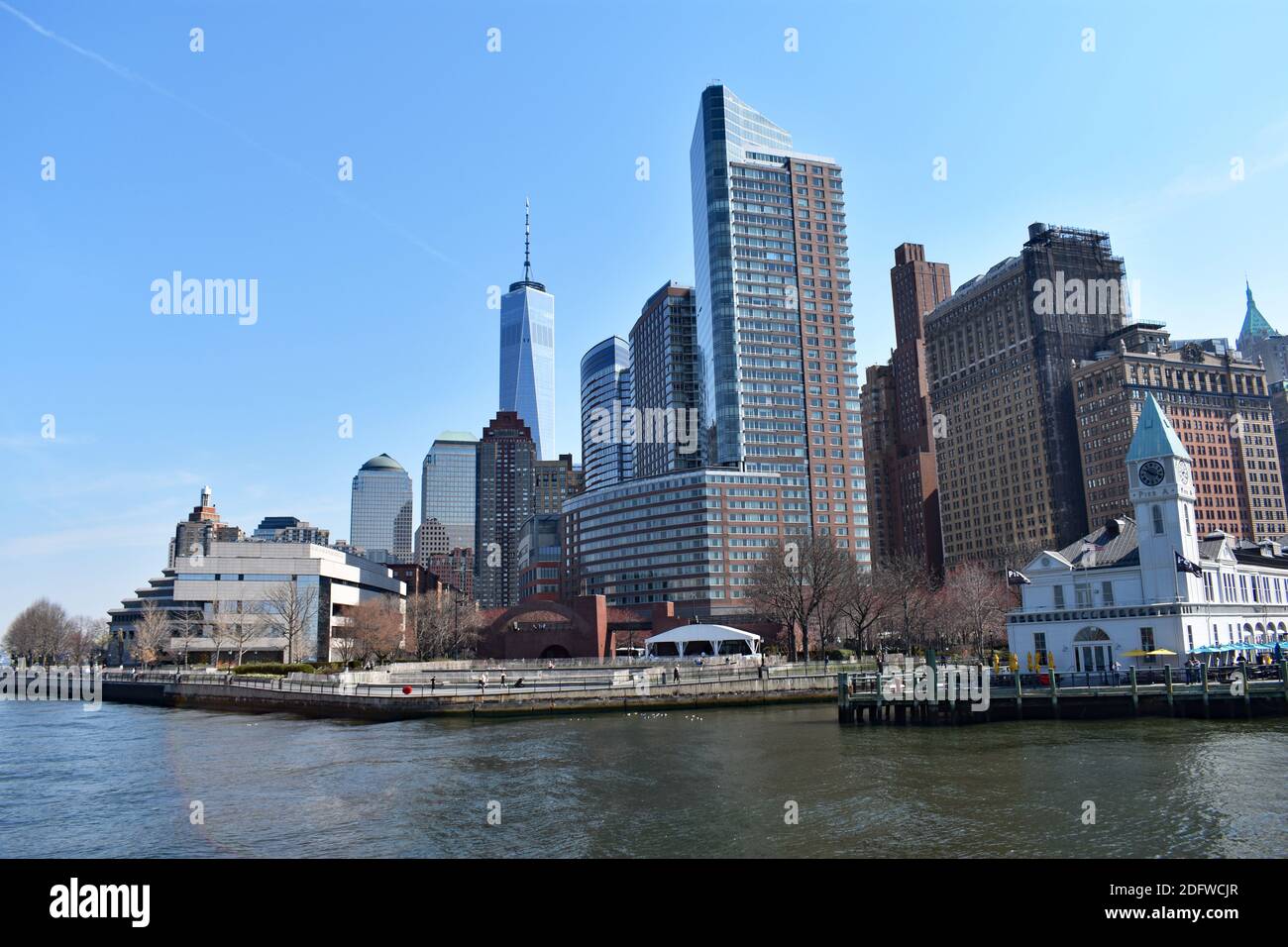 Lo skyline di Lower Manhattan visto dal fiume Hudson in un giorno con cielo blu chiaro. One World Trade Center e Battery Park sono in vista. Foto Stock
