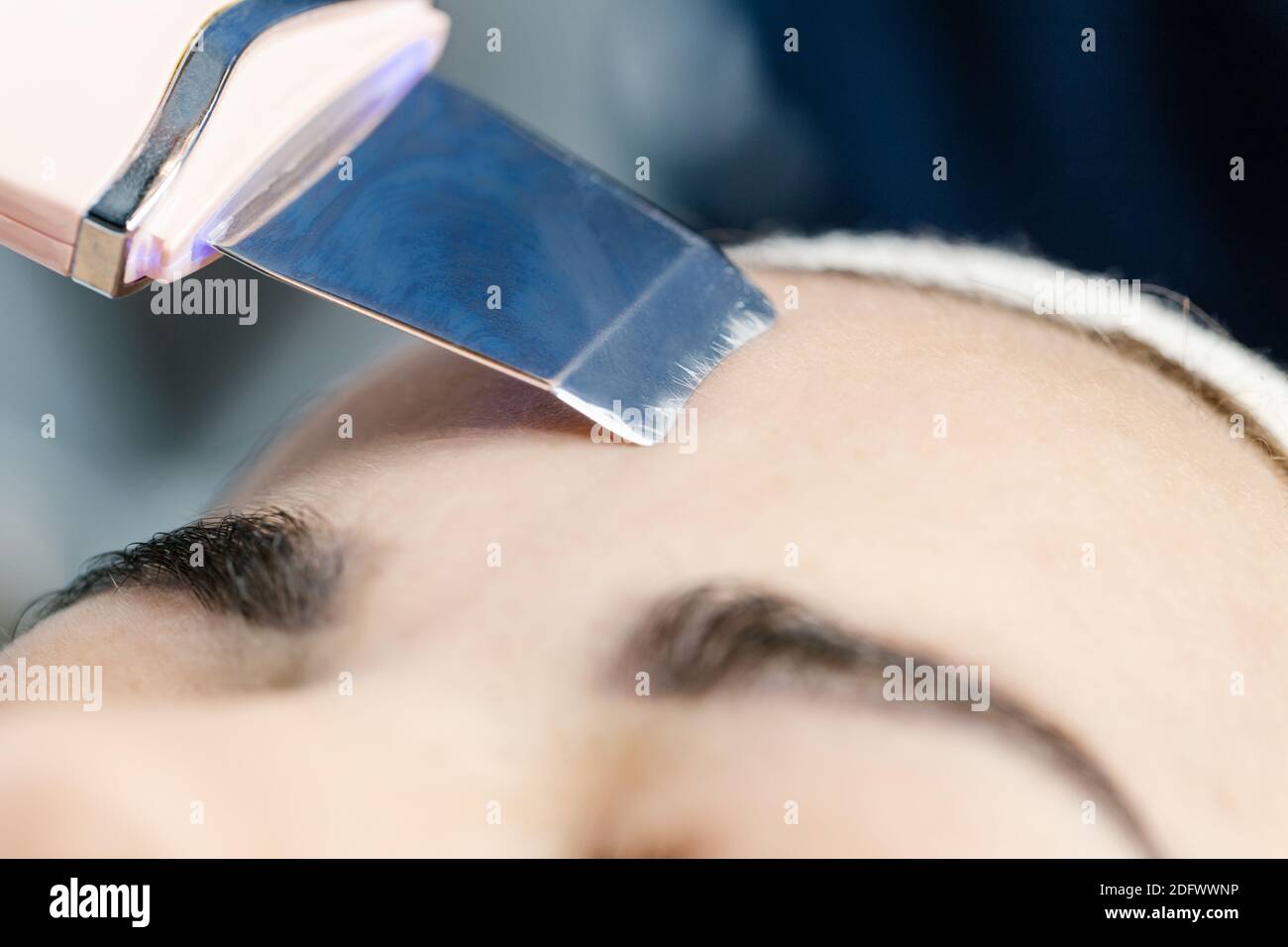 Primo piano la procedura di peeling viso ultrasonico nei saloni di bellezza. Il dispositivo per la pulizia del viso a ultrasuoni. Cosmetologia hardware. Foto Stock