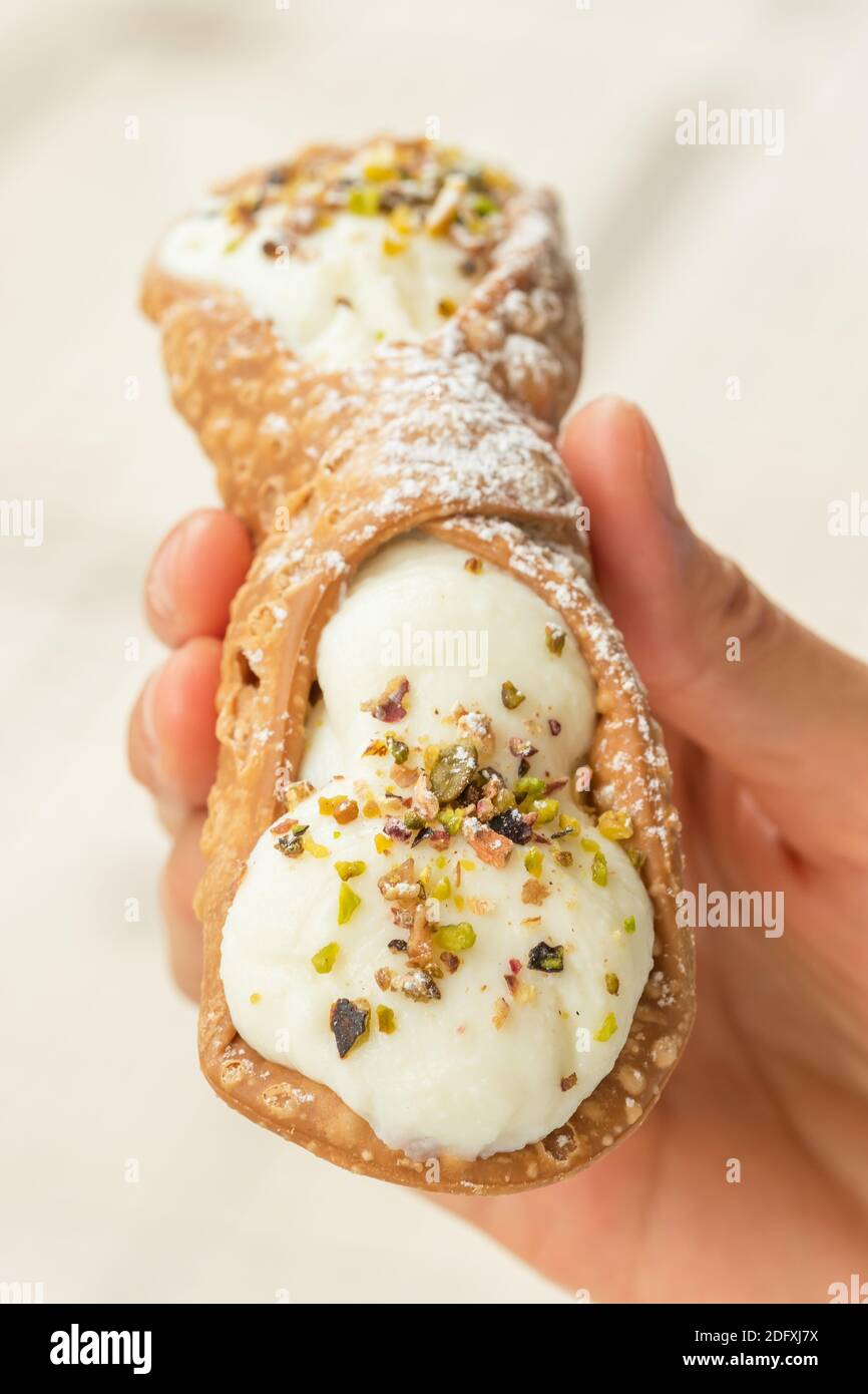 Primo piano di un fresco Cannoli siciliano, tenuto a mano. . Foto Stock