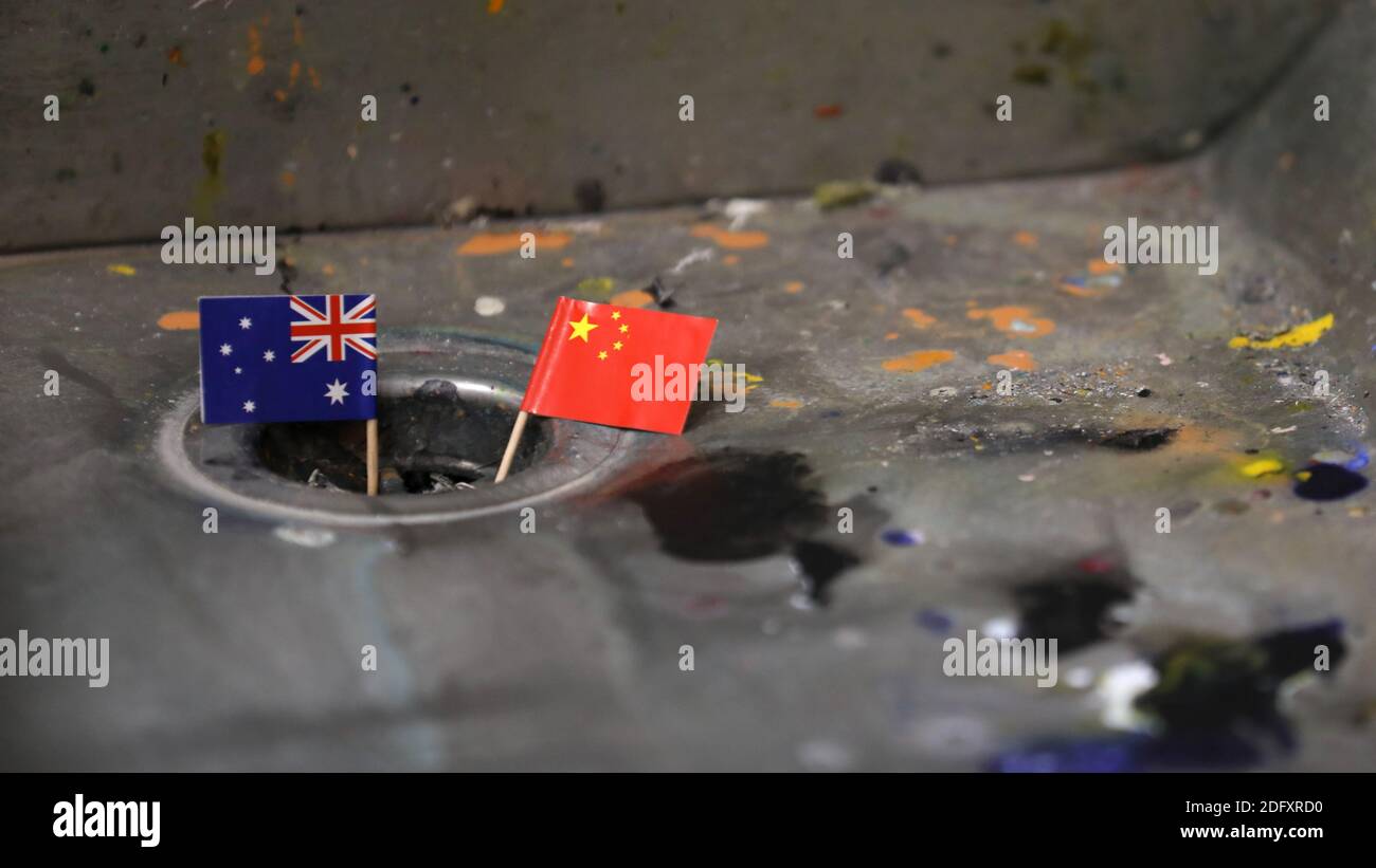Le relazioni australiane e cinesi stanno scendendo alla scolo. Le bandiere nazionali di Australia e Cina sono collocate in un foro del tappo del lavello che rappresenta la corrente tesa Foto Stock
