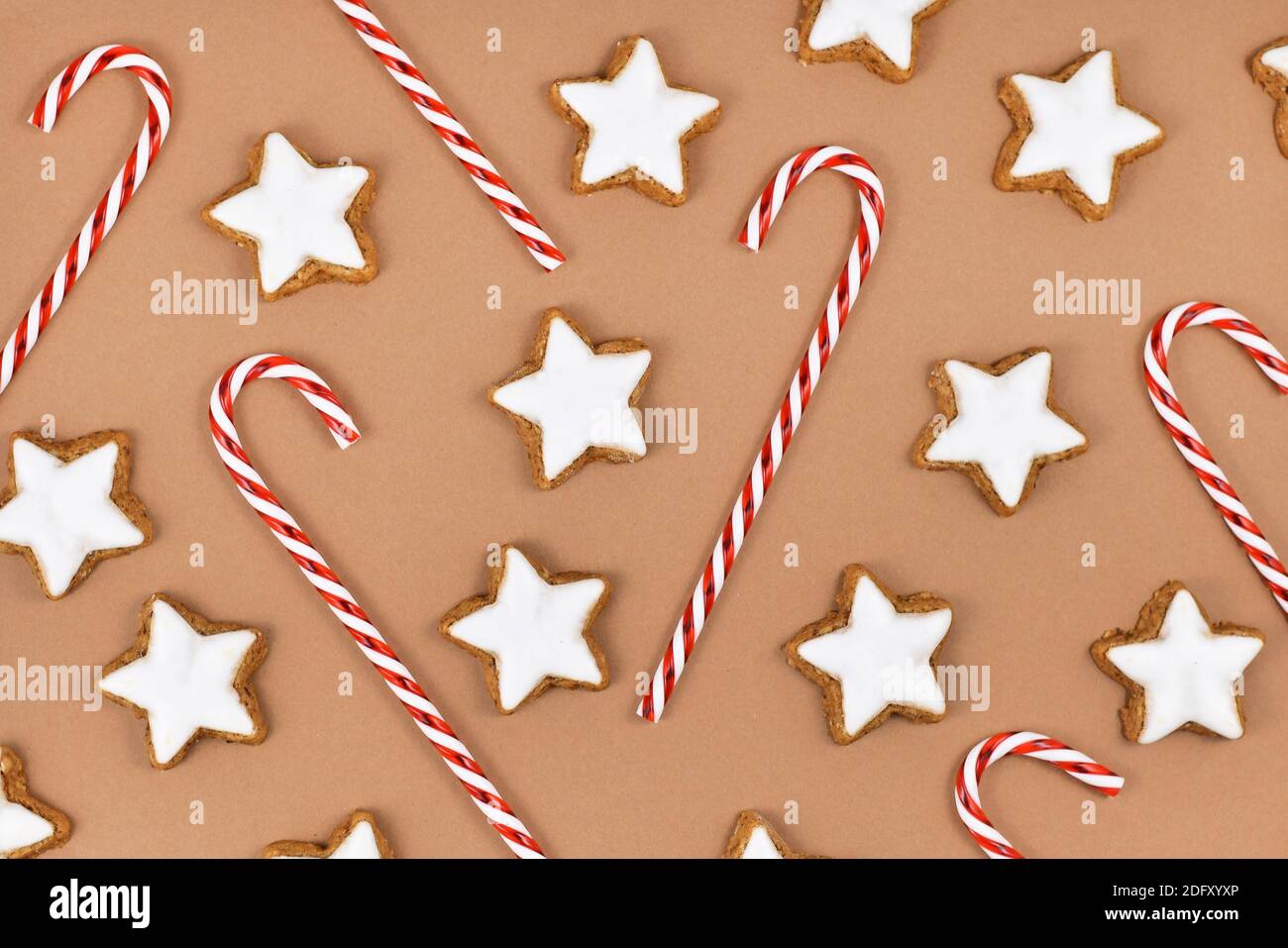 Biscotti di Natale glassati a forma di stella tedeschi chiamati 'Zimtsterne' e caramelle canne su sfondo marrone Foto Stock