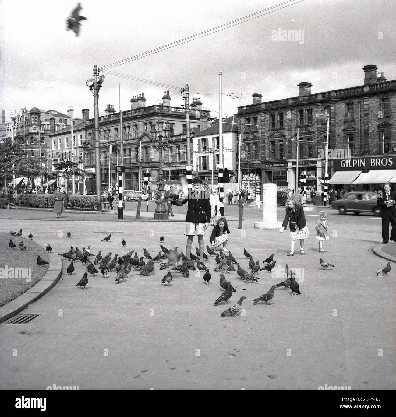 Anni '50, immagine storica, i bambini della scuola giocano con i piccioni nel tranquillo centro di Belfast, Irlanda del Nord, Regno Unito. Foto Stock