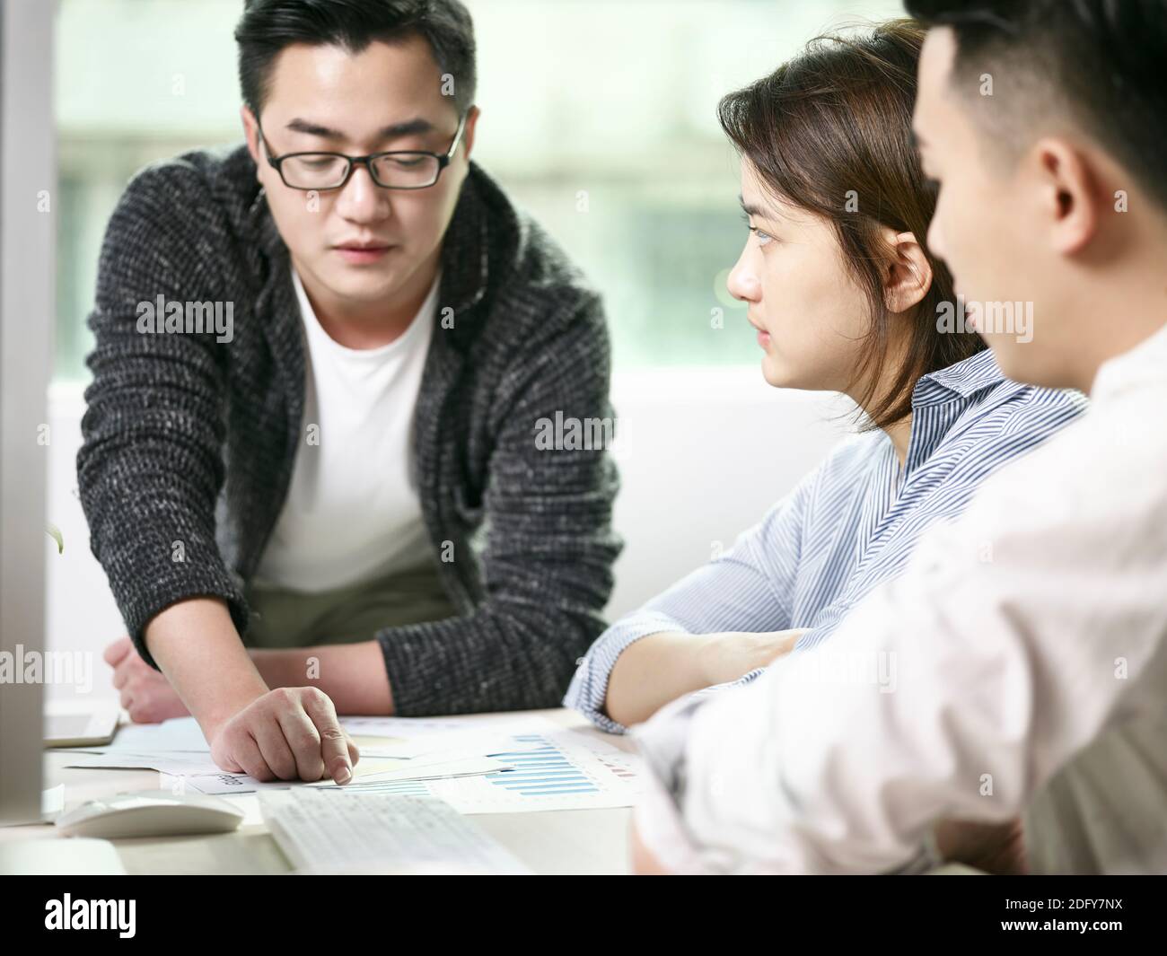 squadra di uomini e donne asiatici che discute di affari in ufficio Foto Stock