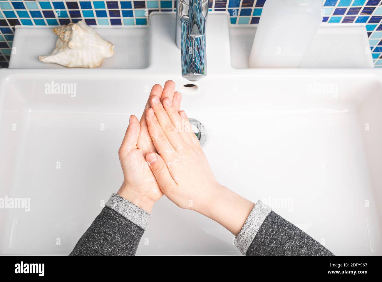 Bambino diligentemente mani che si sporgono eseguendo il lavaggio a mano - misura di protezione di base Contro la diffusione della malattia di Coronavirus COVID-19 Foto Stock