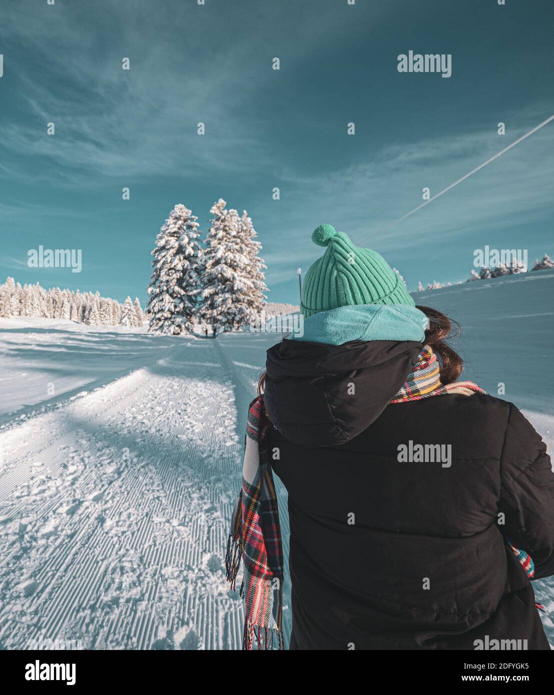 Primo piano di una donna adulta che indossa abiti caldi invernali camminando in un paesaggio invernale innevato di una foresta alpina coperta di neve fresca. Foto Stock