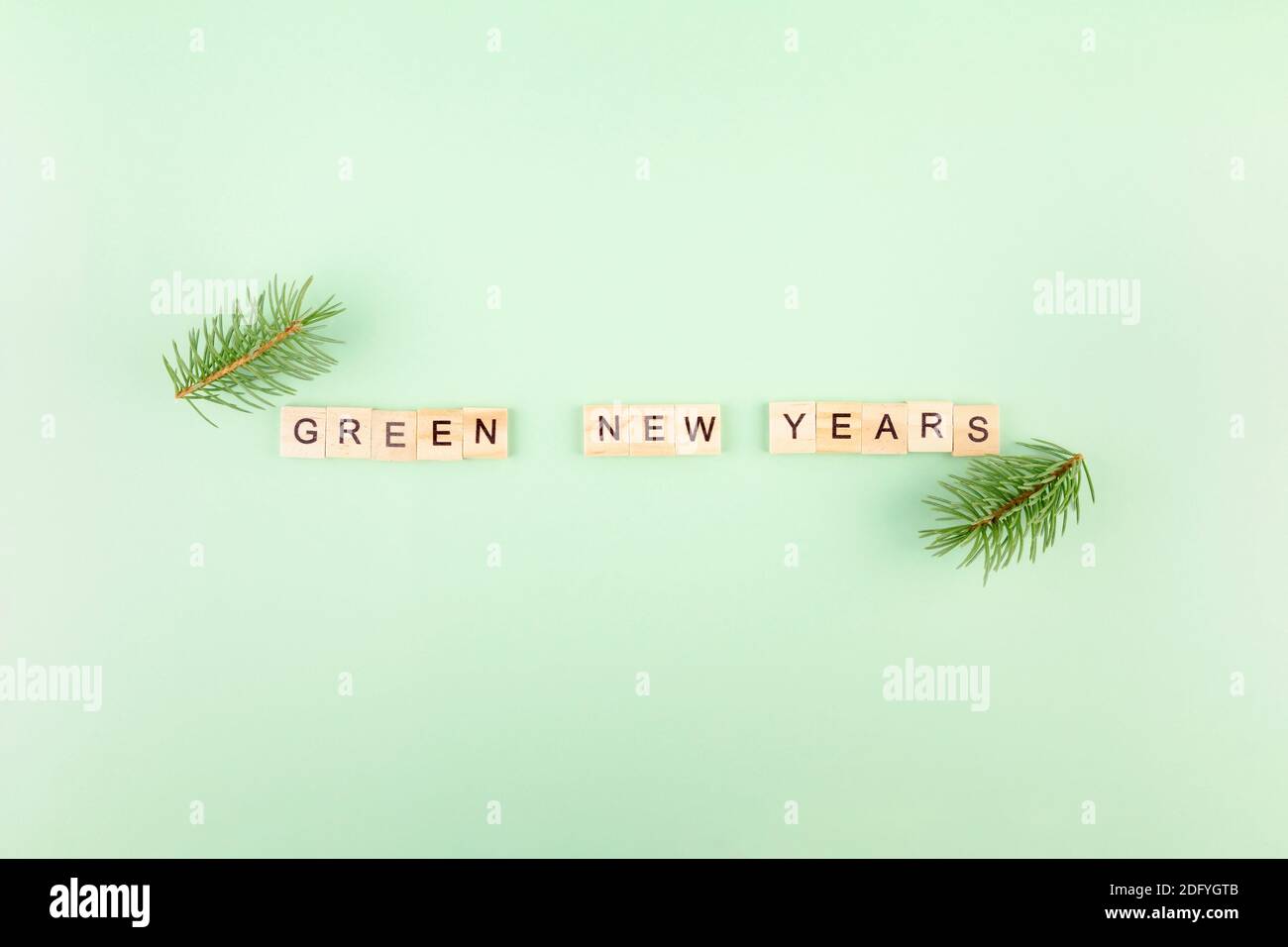 Frase 'Green new years' in lettere di legno su sfondo verde, rami di abete intorno Foto Stock