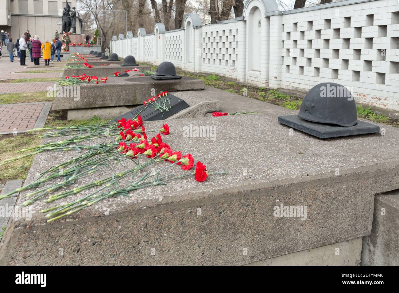 Lapidi - cenotafi con caschi in bronzo, decorati con fiori rossi di garofano, sono disposti in fila al Victory Memorial durante il celebrat Foto Stock