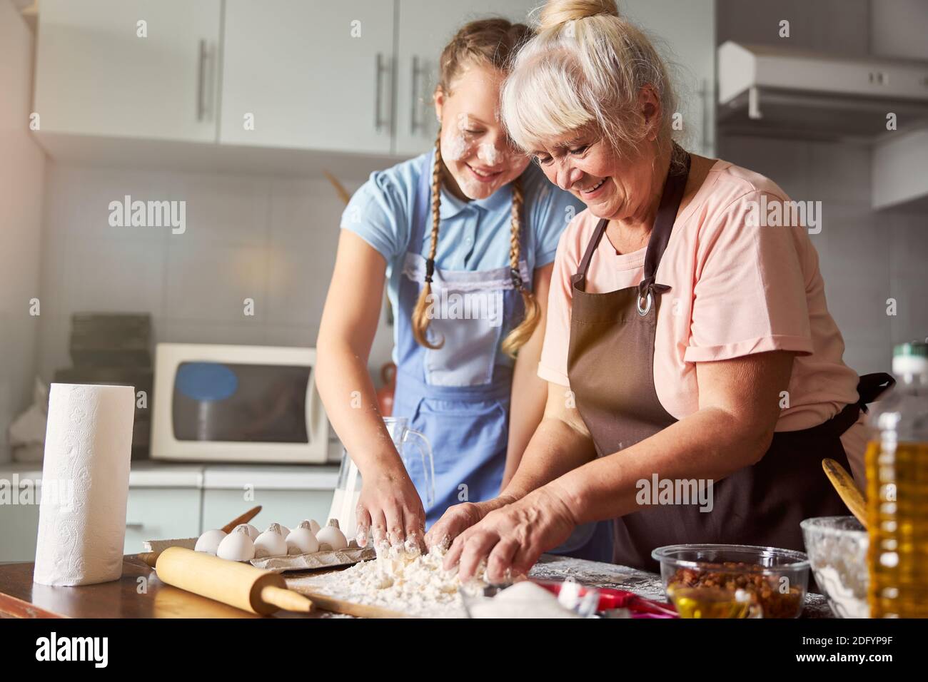 Nonna contentata che ha sua nipote aiutarla in cucina Foto Stock
