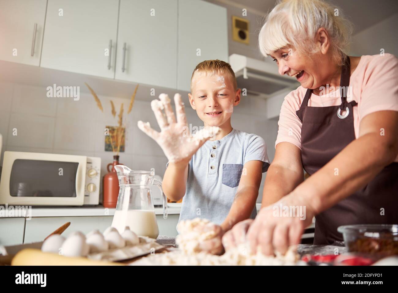 Gioiosa donna anziana e suo nipote che preparano l'impasto Foto Stock
