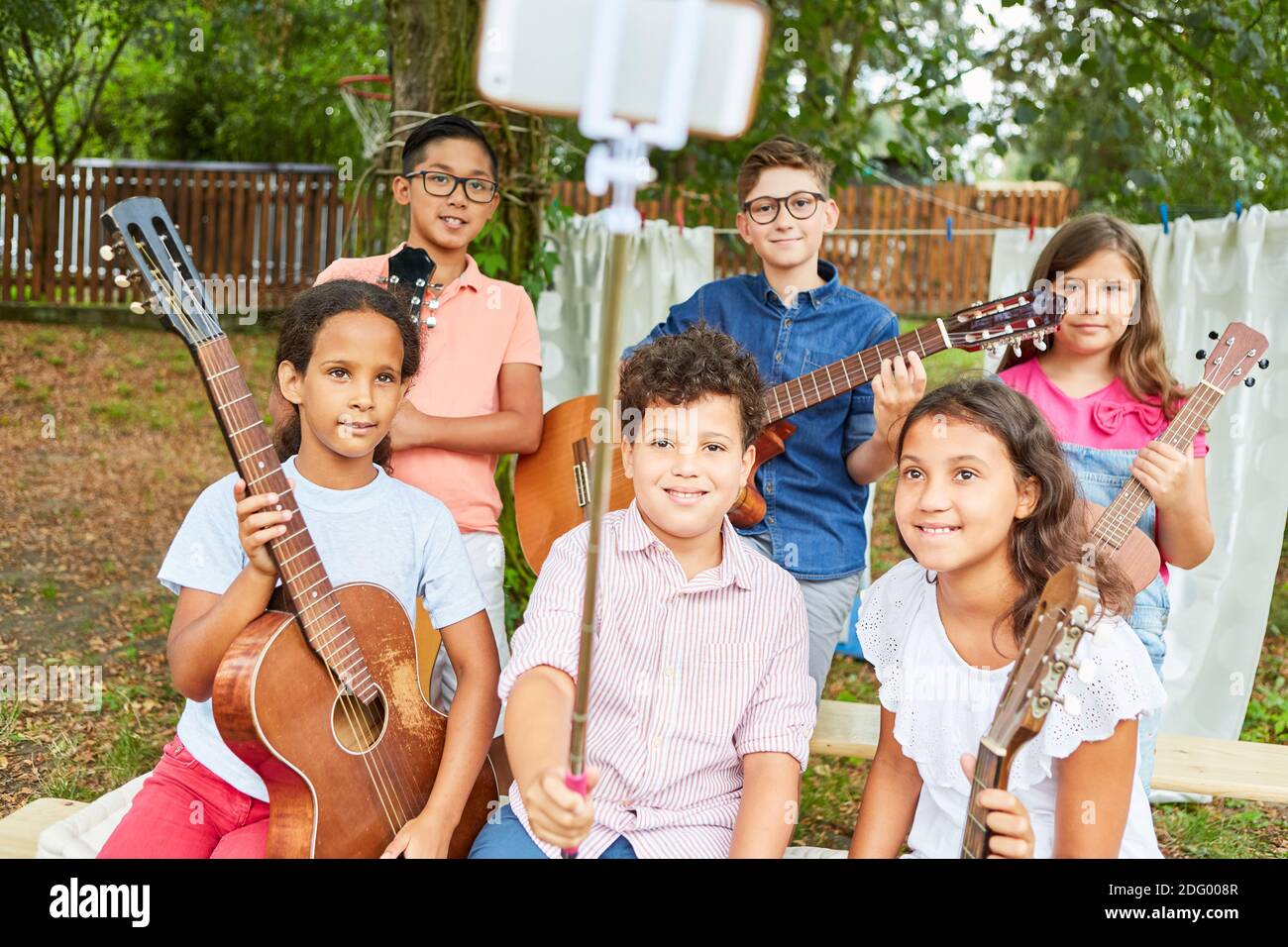 I bambini come un gruppo musicale con chitarre fanno selfie con il bastone selfie al campo di vacanza Foto Stock