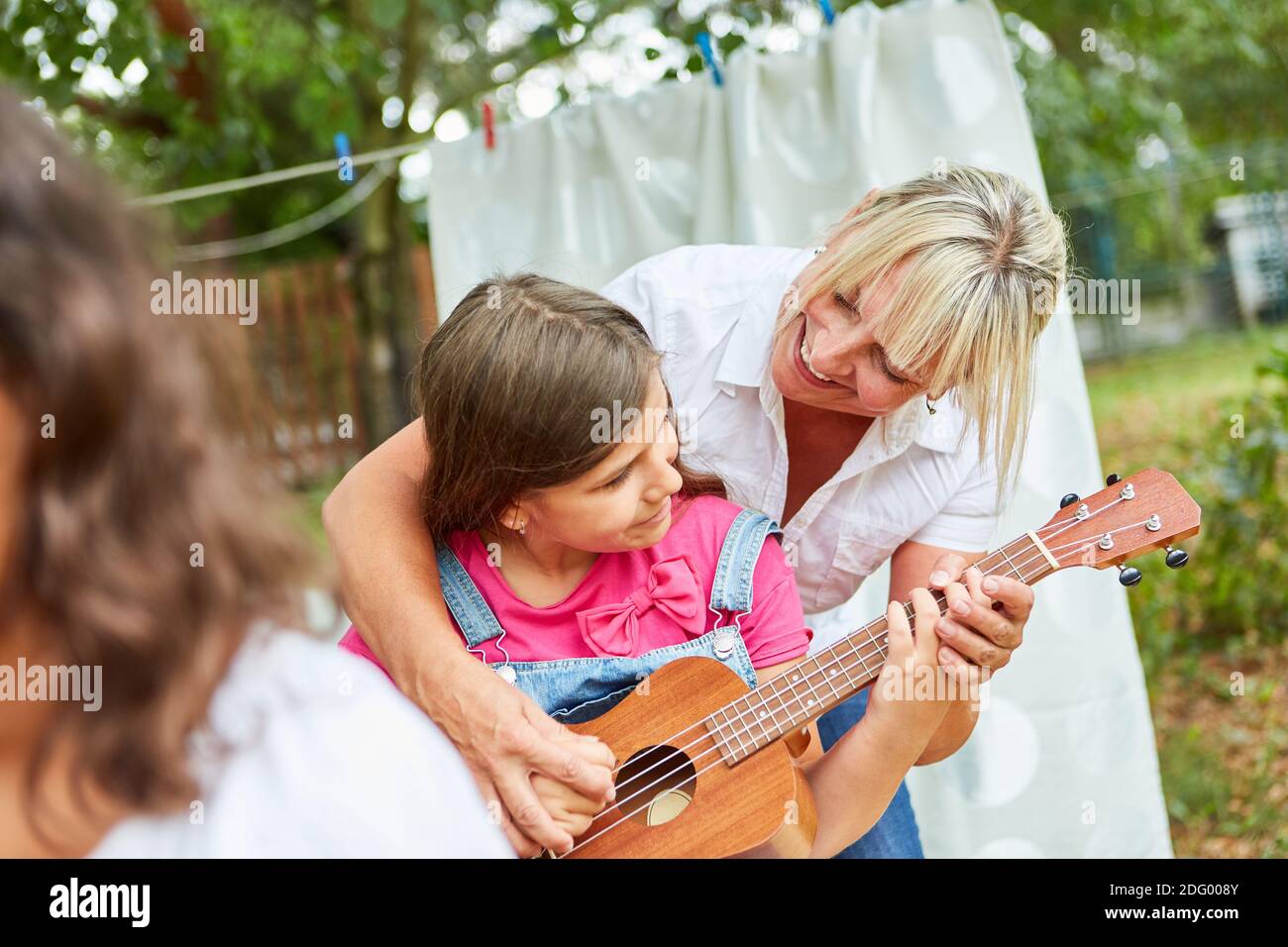 La ragazza pratica suonare la chitarra con l'aiuto dell'insegnante lezione di chitarra al campo estivo Foto Stock