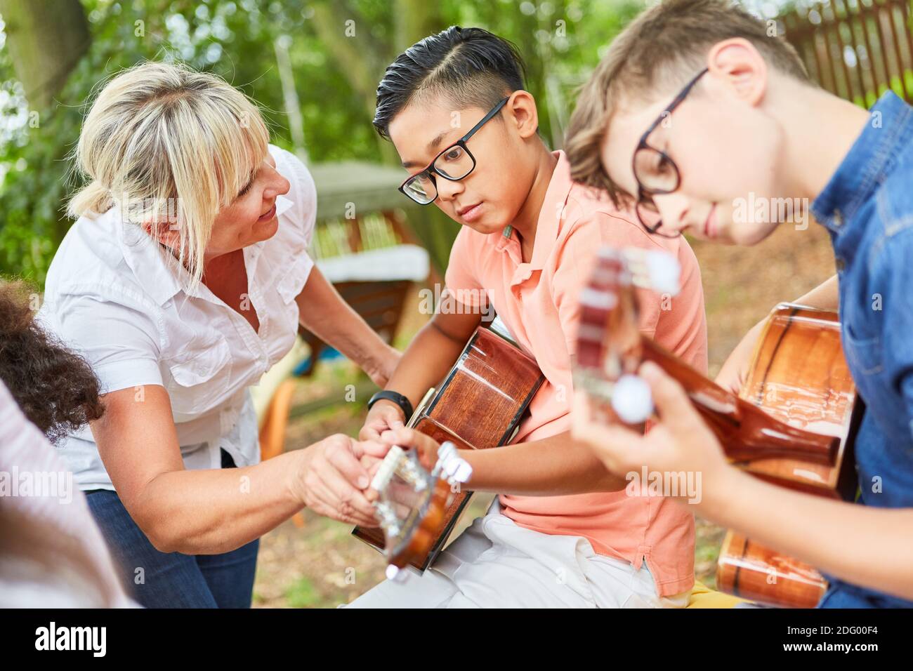 Insegnante e bambini nel corso di chitarra al campo estivo allenarsi per lo spettacolo di talenti Foto Stock