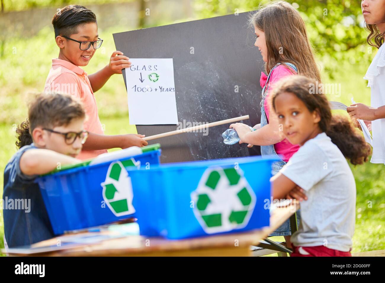 Il gruppo di bambini apprende la sostenibilità e la protezione ambientale in uno spreco campagna di riciclaggio del vetro Foto Stock