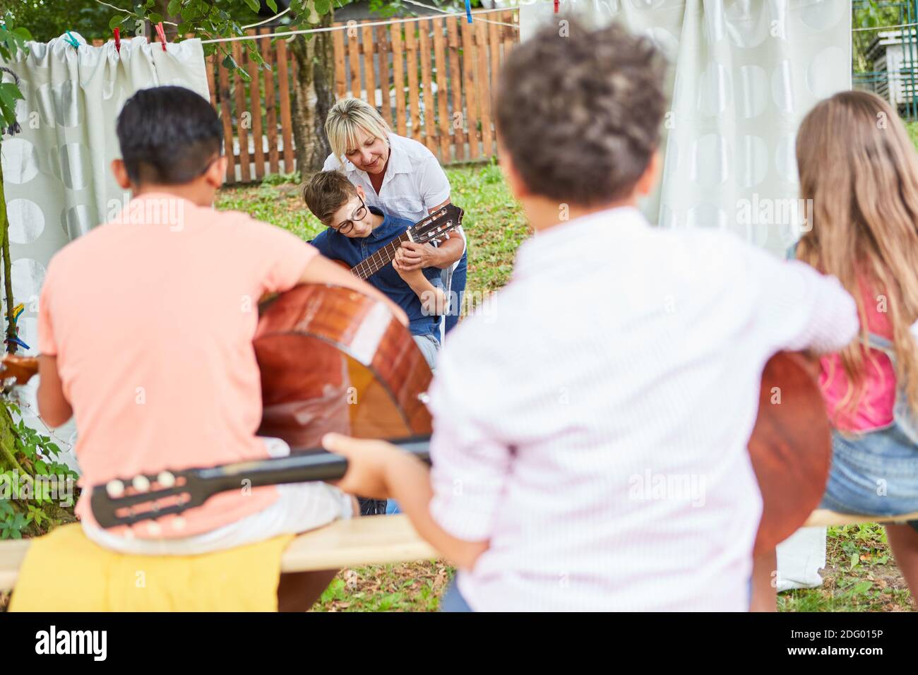 Gruppo di bambini che imparano e si esercitano a suonare la chitarra in classe di chitarra al campo estivo Foto Stock