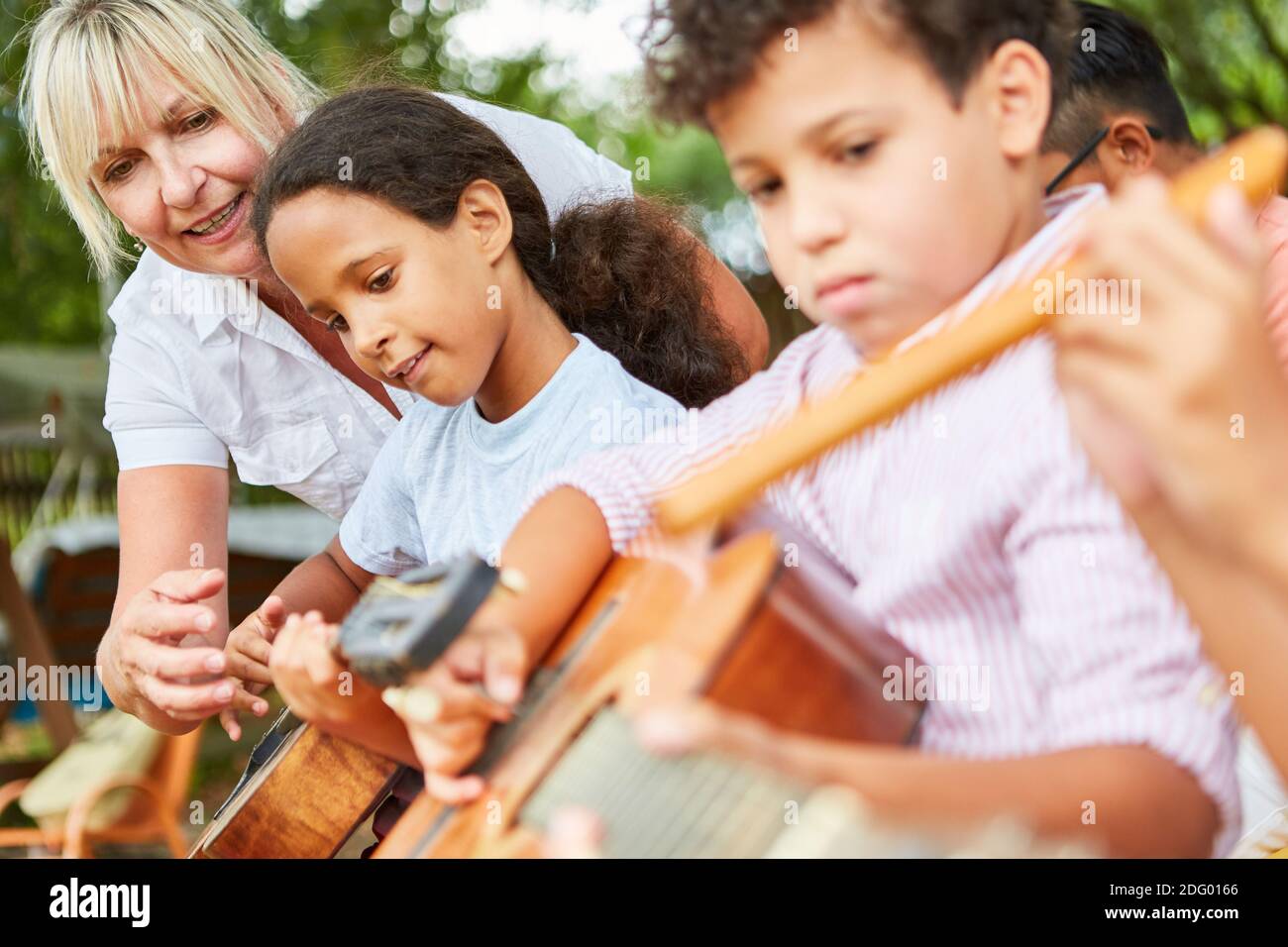 Bambini e insegnanti in classe di chitarra che pratica per il talento spettacolo al campo estivo Foto Stock