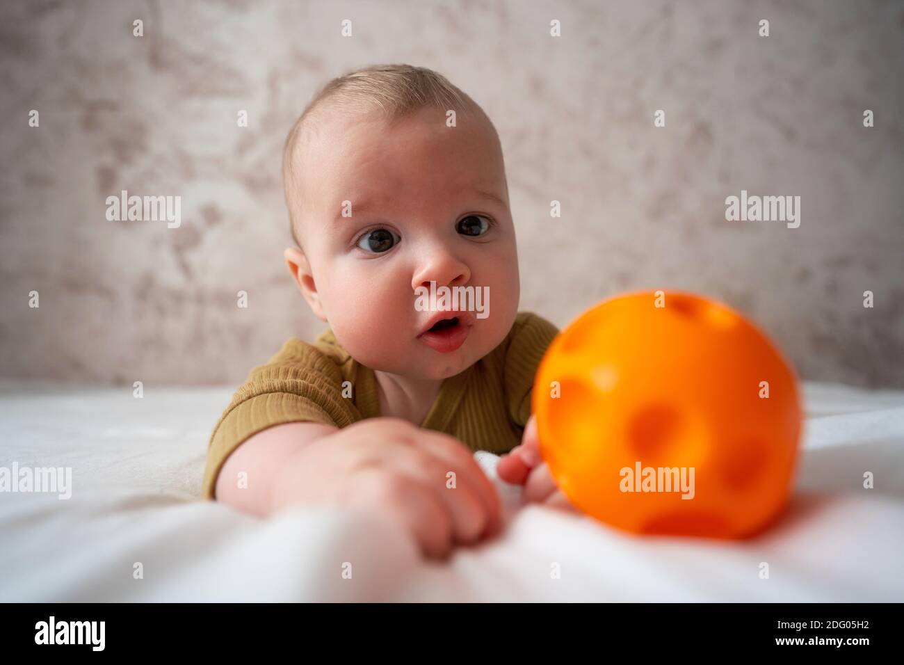Simpatico bambino che gioca con la palla a letto Foto Stock