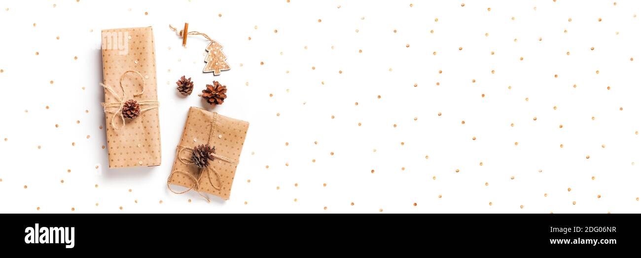 Confezione regalo avvolta in carta artigianale decorata con cono di pino su sfondo bianco, banner lungo, spazio copia, vista dall'alto Foto Stock