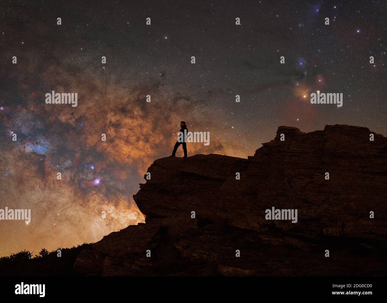 silhouette di una persona su una roccia con il colorato Centro galattico della Via Lattea alle spalle Foto Stock