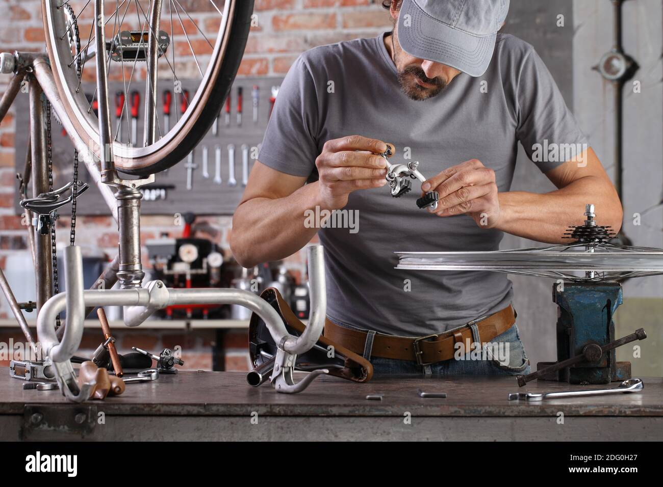 uomo riparare la bicicletta d'epoca in officina sul banco da lavoro con attrezzi, concetto fai da te Foto Stock