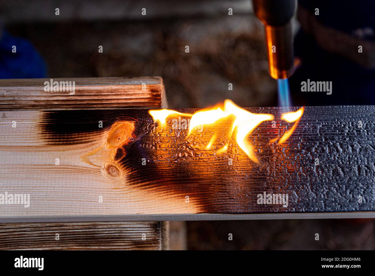 Lavorazione del legno mediante combustione con bruciatore a gas, fuoco aperto, spazzolatura. Concetto di invecchiamento artificiale di prodotti in legno. Foto Stock